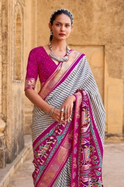Woman wearing a traditional saree with a vibrant pattern in an outdoor setting.